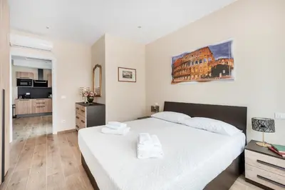 a bedroom with a large white bed and a kitchen at ROMAN DREAM lV in Rome