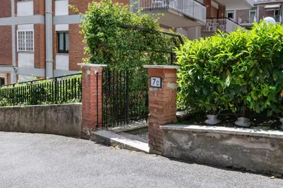 a brick fence with a sign on it next to some bushes at ROMAN DREAM lV in Rome