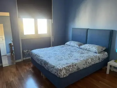 a bedroom with a bed with a blue headboard and a window at Belvedere home in Rome