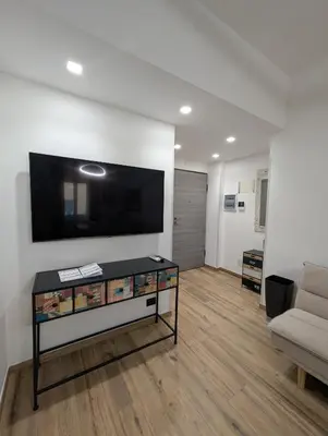a living room with a couch and a tv on a wall at Maison Maurizio Marconi in Rome