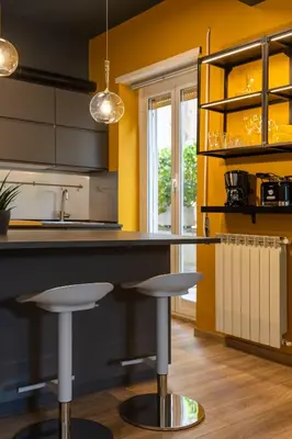 a kitchen with yellow walls and a counter with stools at Maia - Luxury Apartment in Monteverde in Rome