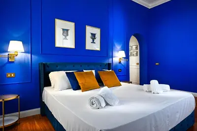a blue bedroom with a large bed with yellow pillows at Royal Blue - Holiday Apartment in Rome