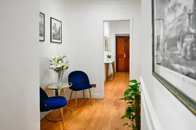 a hallway with blue chairs and a table with a vase of flowers at Royal Blue - Holiday Apartment in Rome