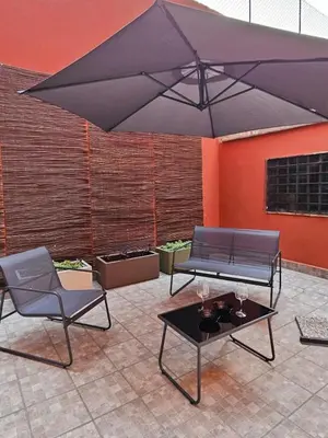 a patio with a black umbrella and two chairs and a table at San Lorenzo Garden Suites in Rome