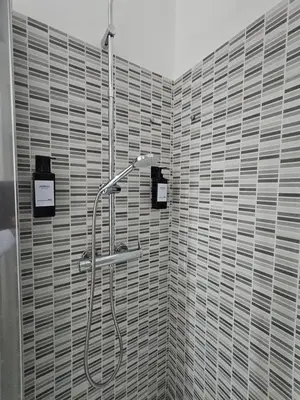 a shower in a bathroom with a tiled wall at San Lorenzo Garden Suites in Rome