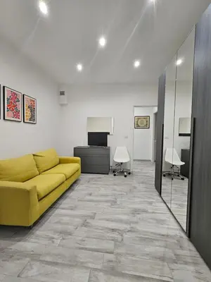 a living room with a yellow couch and a desk at San Lorenzo Garden Suites in Rome