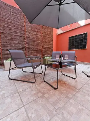 a patio with a table and a black umbrella at San Lorenzo Garden Suites in Rome