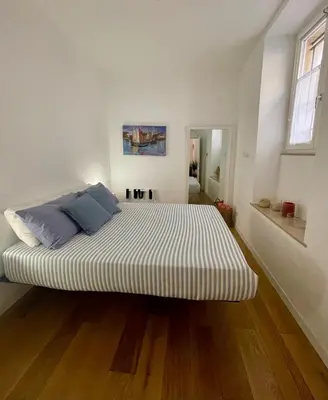 a large bed in a white room with wooden floors at Domus 31 - Colosseum in Rome