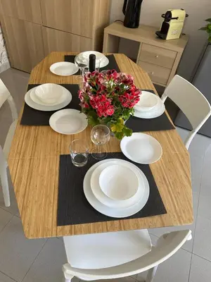 a wooden table with white plates and flowers on it at Appia Suite in Rome