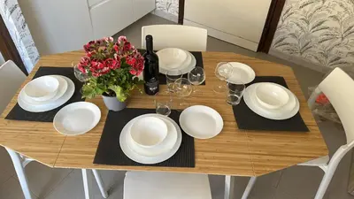a wooden table with white plates and a vase of flowers at Appia Suite in Rome
