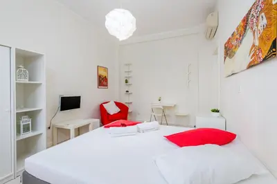 a white bedroom with a bed and a red chair at Domus Aurea3 flat a stone's throw from Colosseum in Rome