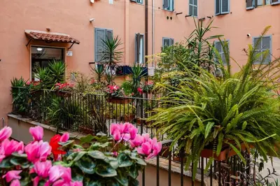 a balcony with pink flowers and plants in front of a building at Domus Aurea3 flat a stone's throw from Colosseum in Rome
