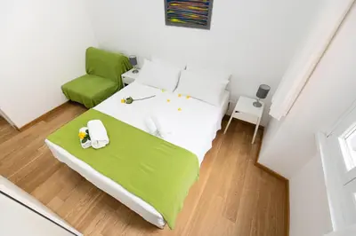 a bedroom with a bed and a green chair at Domus Aurea a stone's throw from the Colosseum in Rome