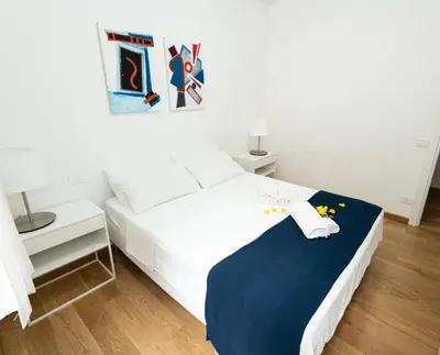 a bedroom with a white bed with a blue blanket at Domus Aurea a stone's throw from the Colosseum in Rome