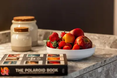 a bowl of fruit on a table next to a book at Interno2 - Cozy flat near Vatican Museums in Rome