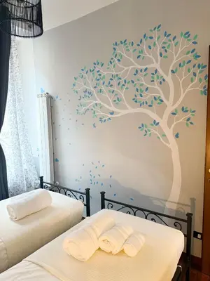 a bedroom with two beds with a tree mural on the wall at Borgo Una Casa Nel Vicolo in Rome