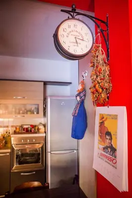 a clock hanging on a wall next to a refrigerator at Casetta Ponte Milvio in Rome