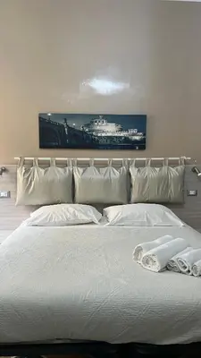 a large white bed with white pillows and a painting at Guest house Aria in Rome
