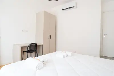 a bedroom with a large white bed with a black chair at Home d'élite Gregory in Rome