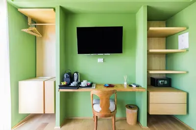 a green room with a desk with a television on a green wall at Rarity Suites in Rome
