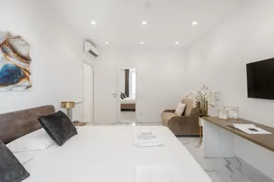 a white living room with a bed and a tv at Eternal House Caulonia in Rome