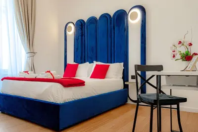 a blue bed with red pillows and a chair in a room at Historical Center in Rome