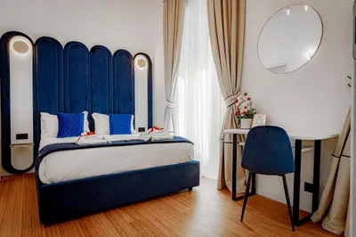 a bedroom with a bed with a blue headboard and a mirror at Historical Center in Rome