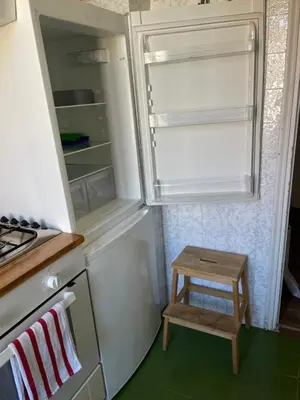 an empty refrigerator with a small stool in a kitchen at Sunny apartment in central Rome in Rome