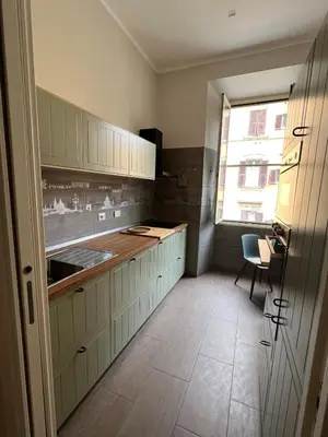 a kitchen with white cabinets and a table and a window at Archouse - Elegant apartment a 10 min dal Colosseo in Rome