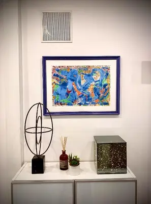 a painting on a wall above a white shelf with a table at Appartamento metro Ponte Lungo in Rome