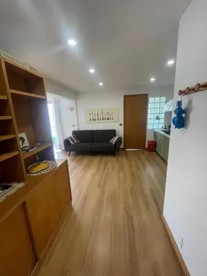 a living room with a black couch and wooden floors at Bright and Cozy Studio Apartment near Trastevere Station in Rome
