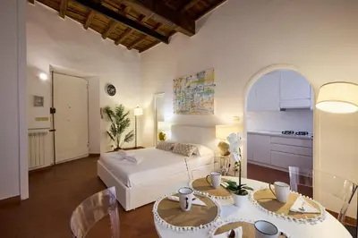 a bedroom with a bed and a table and a kitchen at Navona Maison in Rome