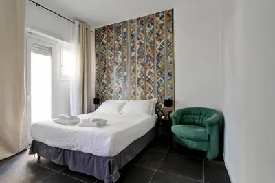 a bedroom with a bed and a green chair at Modern house near Trastevere in Rome