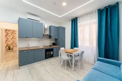 a kitchen with blue cabinets and a table and a blue couch at Stylish Vatican Stay - WiFi Metro Walk Everywhere in Rome