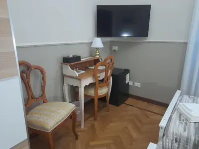a room with a desk with two chairs and a television at Il Sole di Roma in Rome