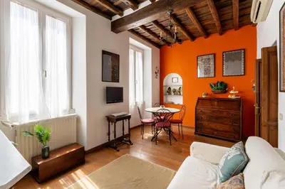 a living room with orange walls and a table at Domus Leopardo, Typical Trastevere Flat in Center in Rome