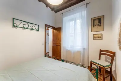 a bedroom with a bed and a chair and a window at Domus Leopardo, Typical Trastevere Flat in Center in Rome