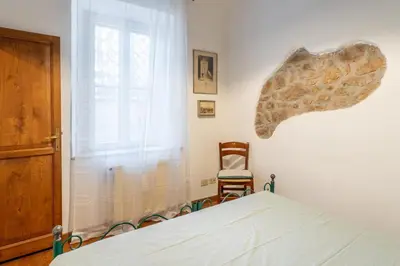 a bedroom with a bed and a chair and a window at Domus Leopardo, Typical Trastevere Flat in Center in Rome