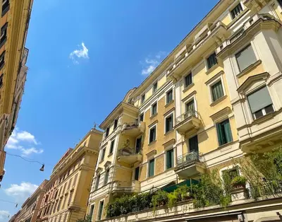 a large yellow building with windows and plants at MARIA TERESA Apartment II - Refined Living with Excellent City Links - Via Alessandria - QUARTIERE TRIESTE in Rome