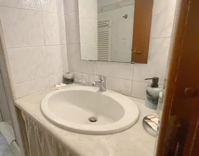a bathroom with a white sink and a mirror at MARIA TERESA Apartment II - Refined Living with Excellent City Links - Via Alessandria - QUARTIERE TRIESTE in Rome