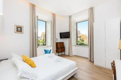 a bedroom with a white bed and two windows at Cola di Rienzo Apartment by Rental in Rome in Rome