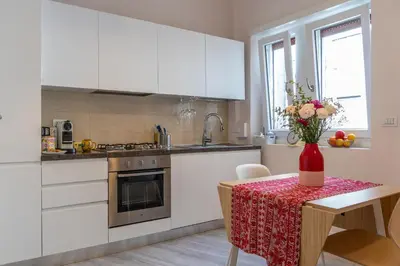 a kitchen with white cabinets and a table with a vase of flowers at 18 Vatican Penthouse in Rome