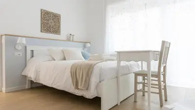 a white bedroom with a bed and a desk at Armonia Mediterranea Apartments in Rome