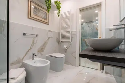 a white bathroom with a sink and a toilet at Deluxe Apartment - Jacuzzi & Cinema, 500m to Metro B, 6-8 pax in Rome