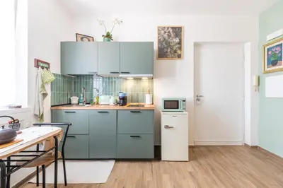 a kitchen with blue cabinets and a table at Vatican Cozy Studio in Rome