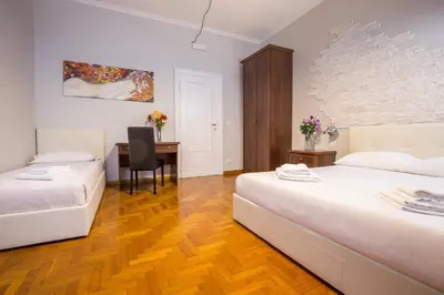 two beds in a room with a desk and a chair at Royal House Vaticano in Rome