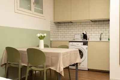 a kitchen with a table with green chairs and a washing machine at Santa Maria Maggiore & Colosseo - Domus Aurea by Hôtea in Rome