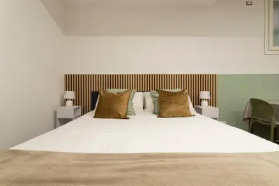 a large bed with white sheets and brown pillows at Santa Maria Maggiore & Colosseo - Domus Aurea by Hôtea in Rome