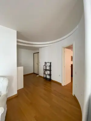 an empty living room with white walls and wood floors at Nina House Roma in Rome