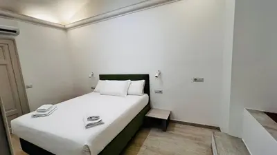 a small room with a bed with white sheets at My house in Rome